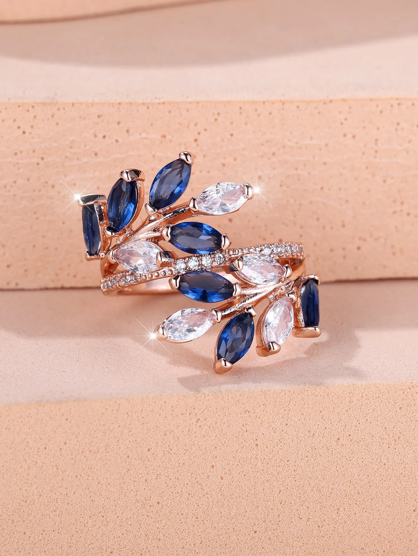 Adjustable copper leaf fashion ring with a central zircon stone on a model's hand, showing rose gold and platinum colour variants.