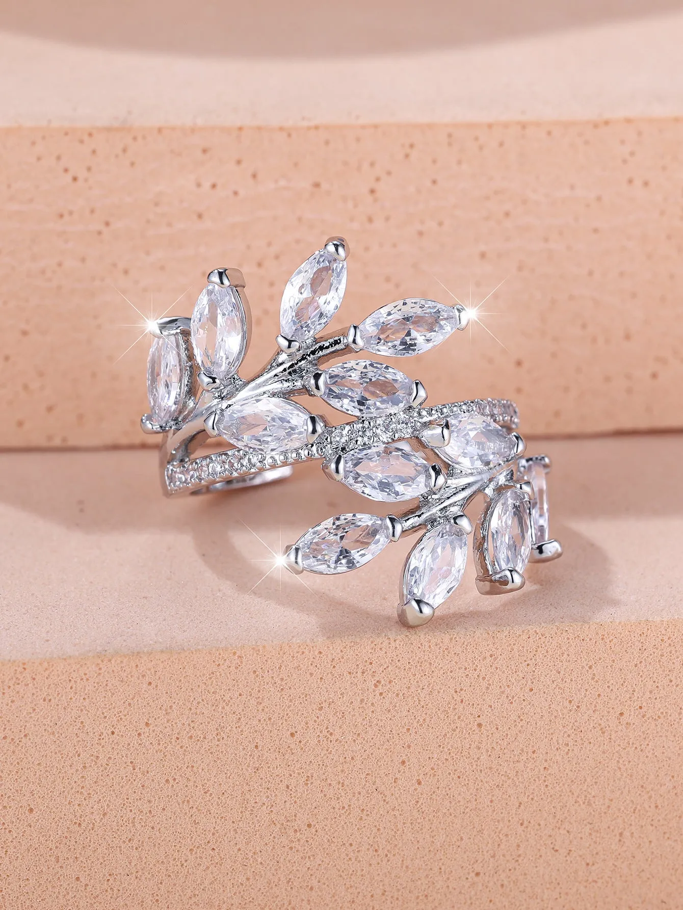 Adjustable copper leaf fashion ring with a central zircon stone on a model's hand, showing rose gold and platinum colour variants.