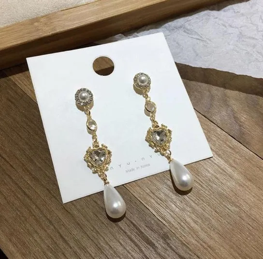 Gold pearl drop earrings with heart-shaped alloy frame and single pearl pendant on gold-tone finish
