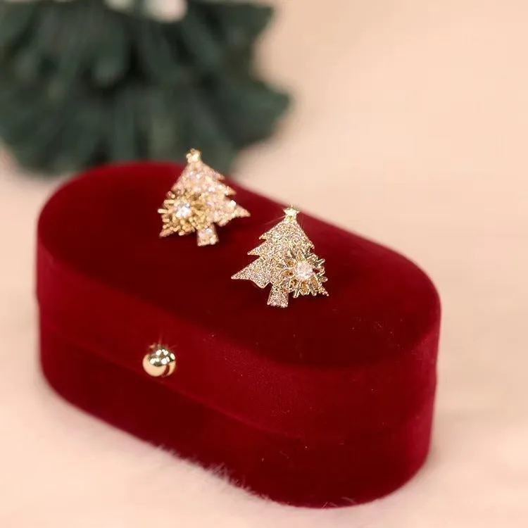 Pair of rotatable Christmas tree stud earrings with rhinestone snowflake detail in gold on a white background