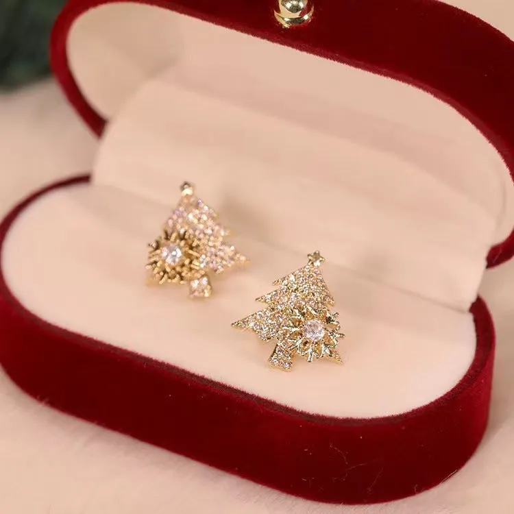 Pair of rotatable Christmas tree stud earrings with rhinestone snowflake detail in gold on a white background