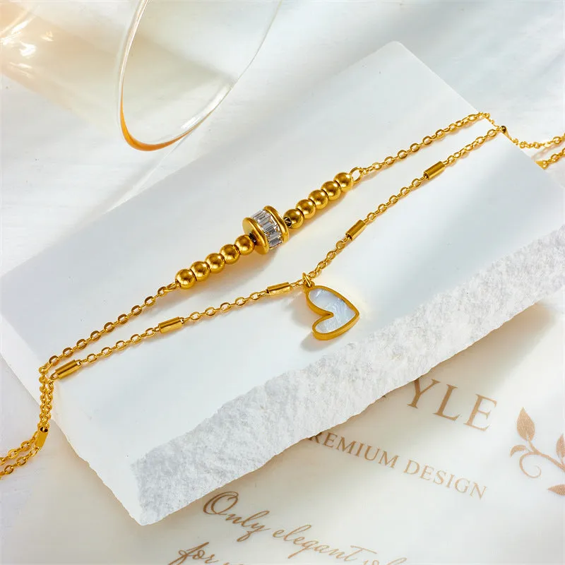 Gold titanium steel double-layer ankle chain with love heart charm and tassel on a white background