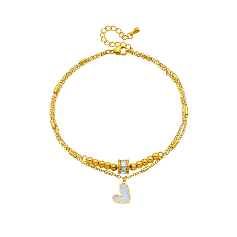 Gold titanium steel double-layer ankle chain with love heart charm and tassel on a white background
