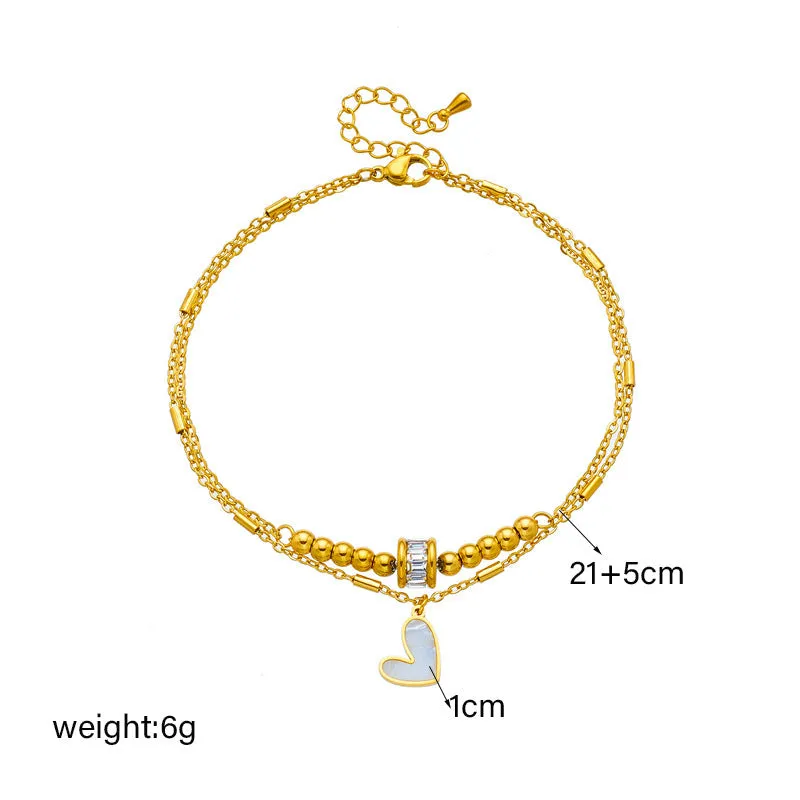 Gold titanium steel double-layer ankle chain with love heart charm and tassel on a white background