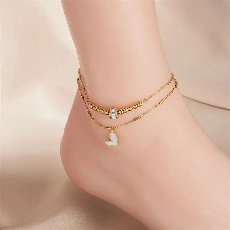 Gold titanium steel double-layer ankle chain with love heart charm and tassel on a white background