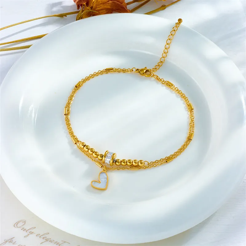 Gold titanium steel double-layer ankle chain with love heart charm and tassel on a white background