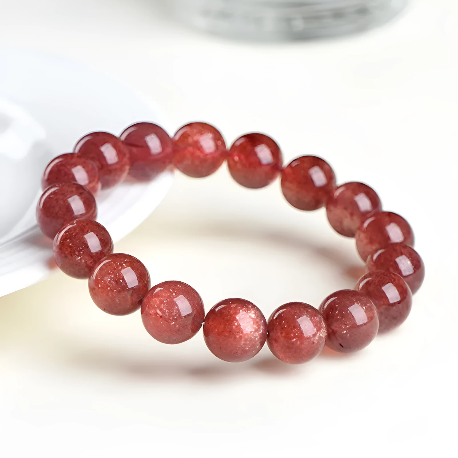 A stretch bracelet with round, pink strawberry quartz beads on an elasticated cord, shown in different size options.