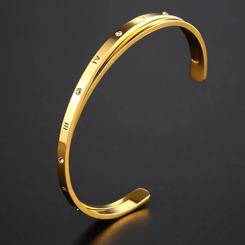Open-ended stainless steel bracelet with inlaid zircon stones and a love charm in rose gold colour.