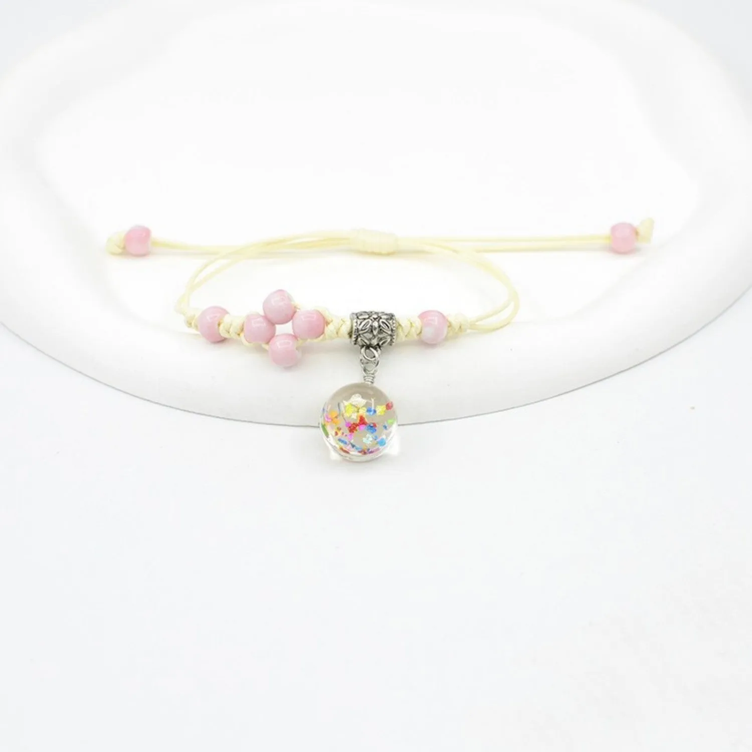 Hand-woven glass bracelet with large beads containing dried flowers and lace decorations, shown in blue.