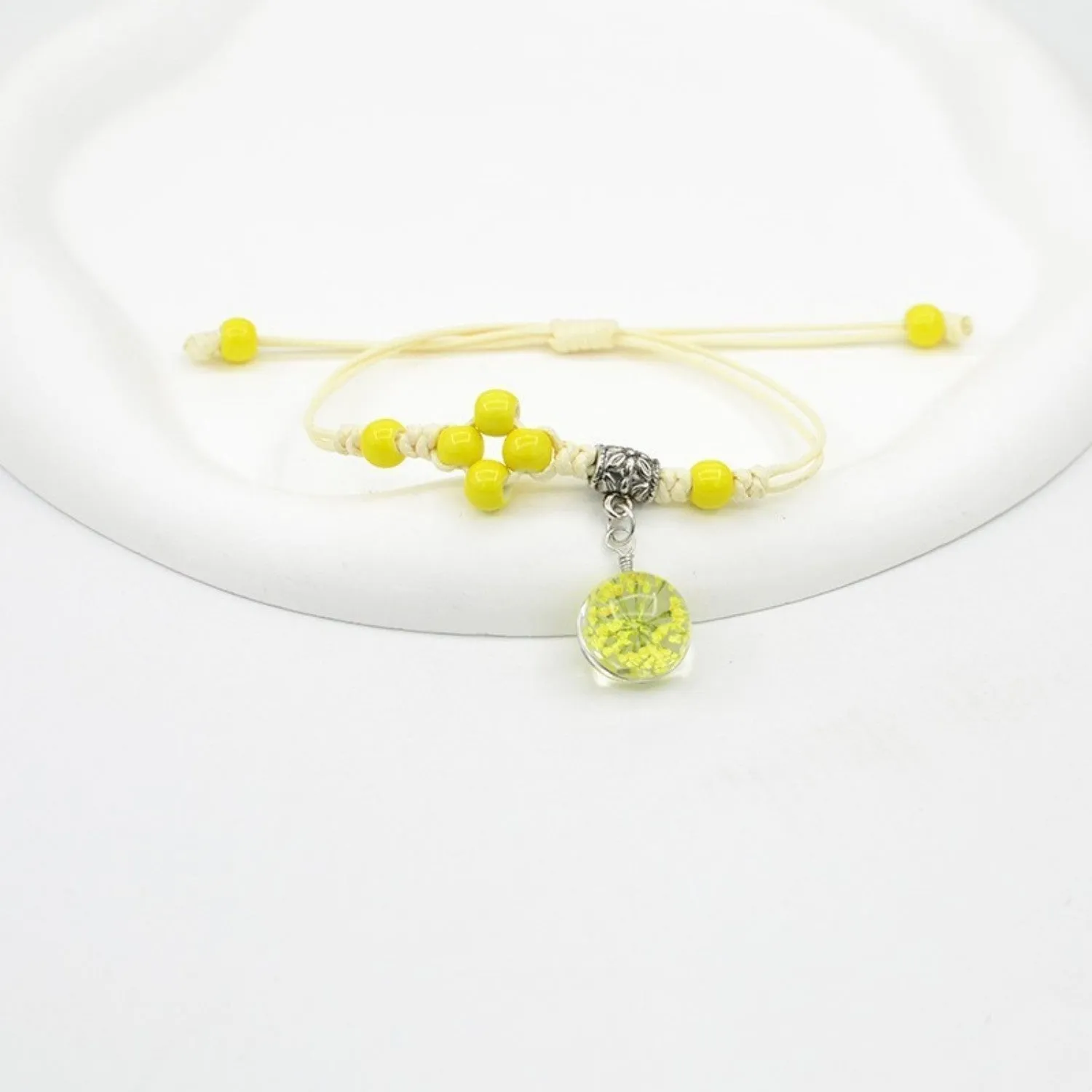 Hand-woven glass bracelet with large beads containing dried flowers and lace decorations, shown in blue.