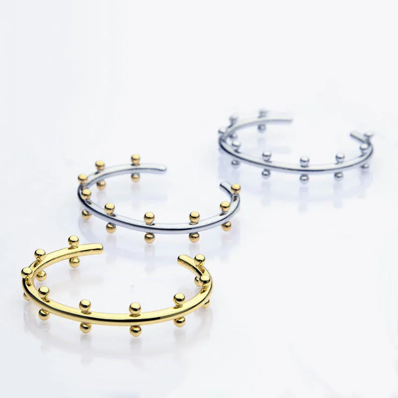 Stainless steel C-shaped bean beads with textured rivet design in gold, steel, and steel gold colours next to an alloy bracelet.