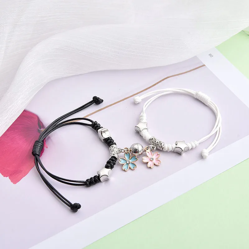 Pair of magnetic alloy bracelets with crown and heart charm designs on a wrist.