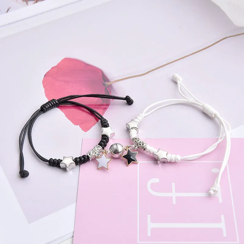 Pair of magnetic alloy bracelets with crown and heart charm designs on a wrist.