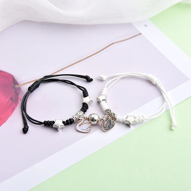 Pair of magnetic alloy bracelets with crown and heart charm designs on a wrist.