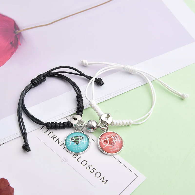 Pair of magnetic alloy bracelets with crown and heart charm designs on a wrist.