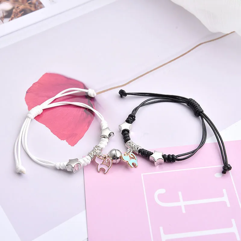 Pair of magnetic alloy bracelets with crown and heart charm designs on a wrist.