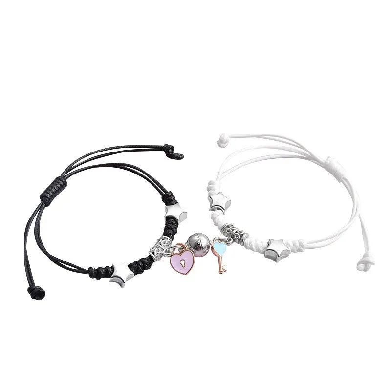 Pair of magnetic alloy bracelets with crown and heart charm designs on a wrist.