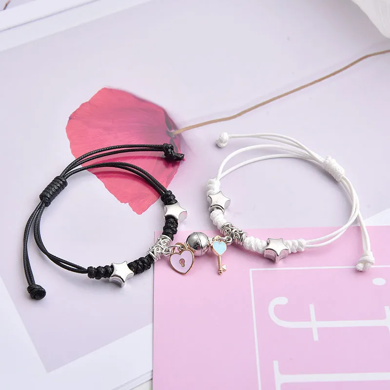 Pair of magnetic alloy bracelets with crown and heart charm designs on a wrist.