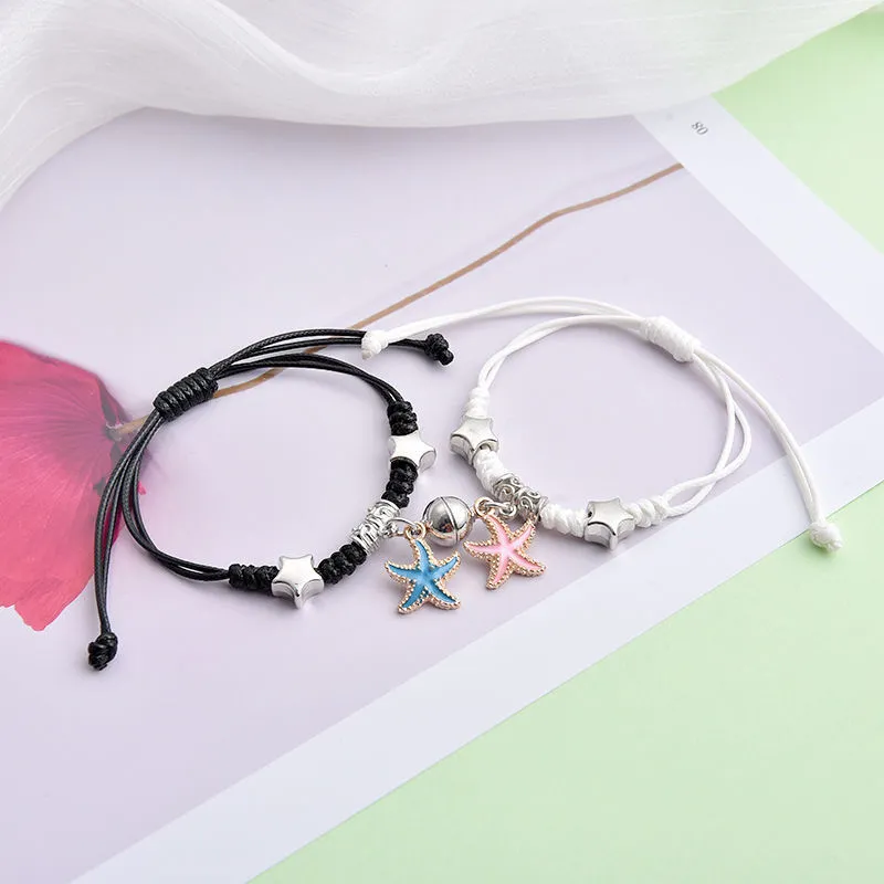 Pair of magnetic alloy bracelets with crown and heart charm designs on a wrist.