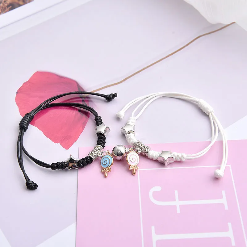 Pair of magnetic alloy bracelets with crown and heart charm designs on a wrist.