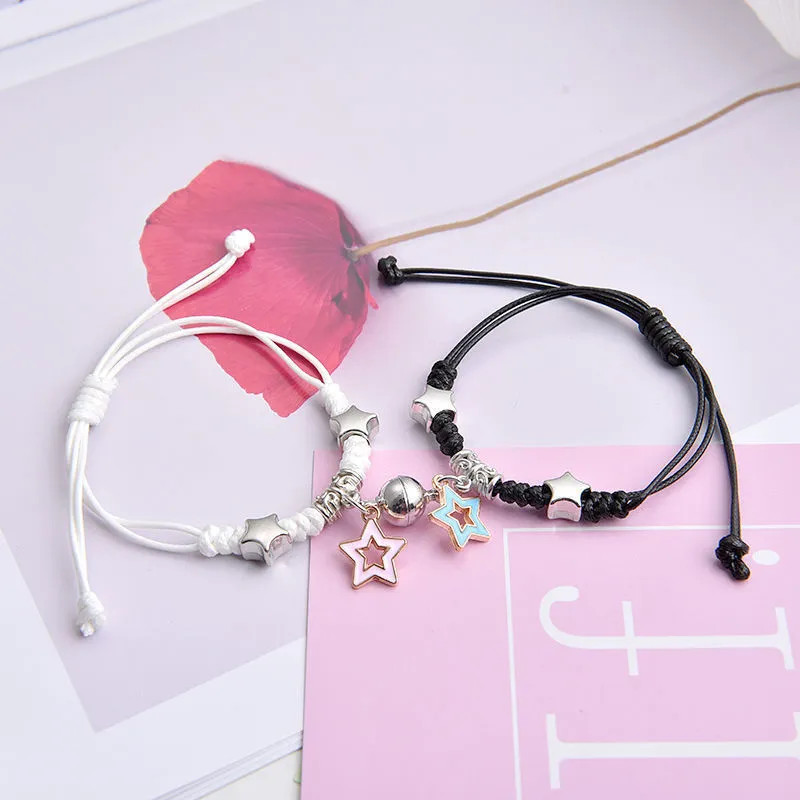 Pair of magnetic alloy bracelets with crown and heart charm designs on a wrist.