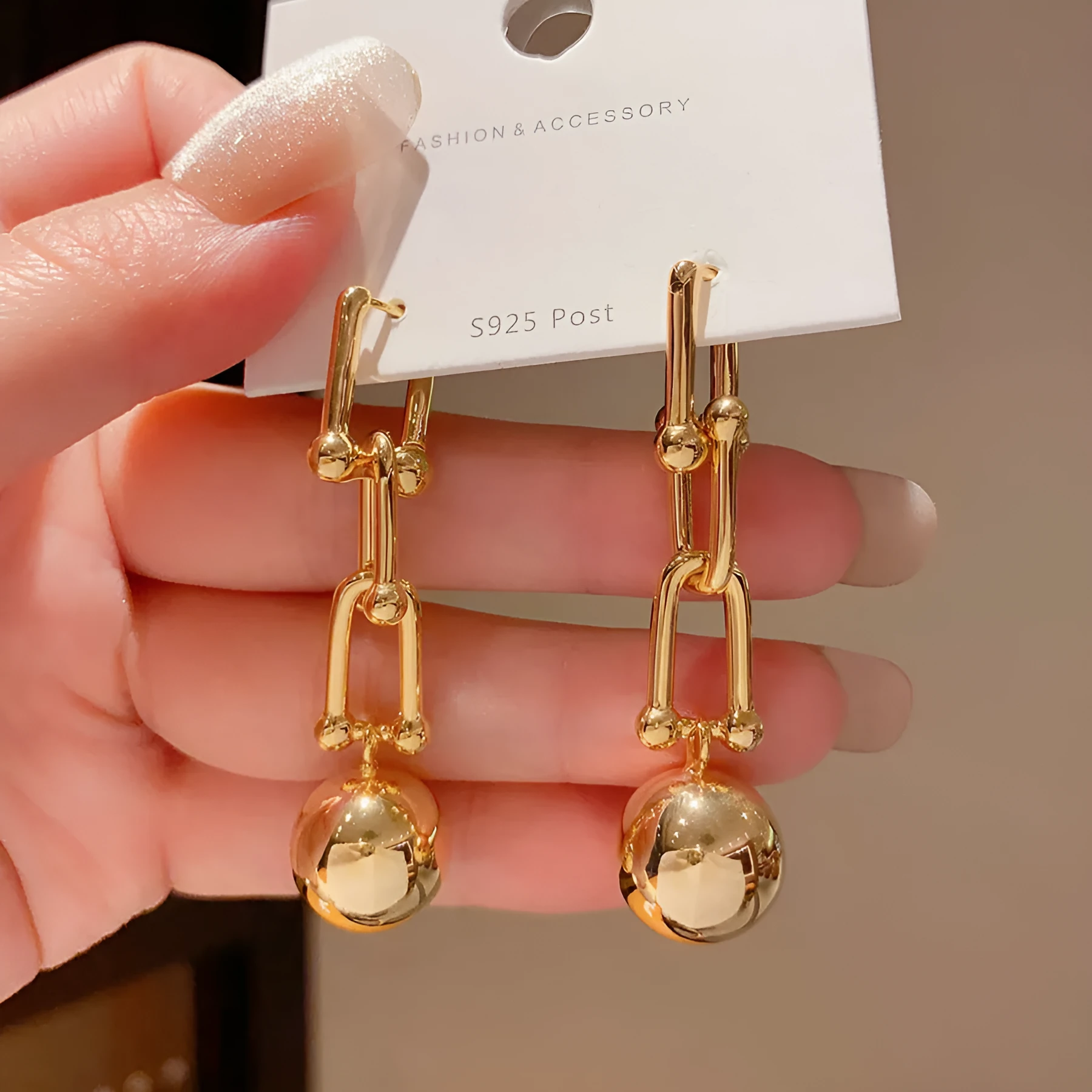 Gold long fringe earrings on display showing geometric line design and electroplated metal finish