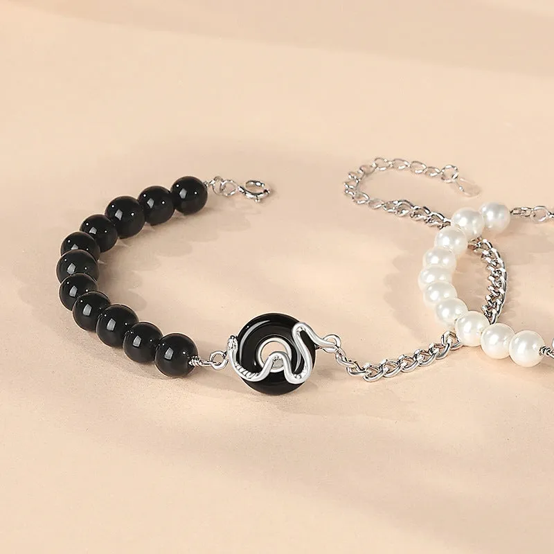 A New Chinese style 925 sterling silver couple's bracelet with a safe buckle, snake motif, and a central obsidian pearl.