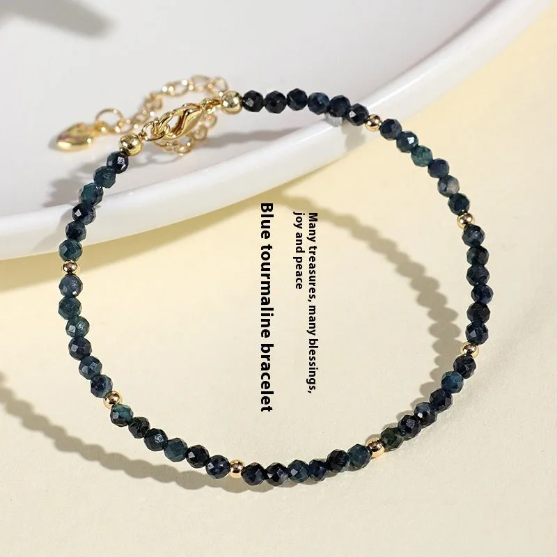 Close-up of a women's bracelet with 3mm blue tourmaline cut beads and silver-toned spacer beads on a wrist.