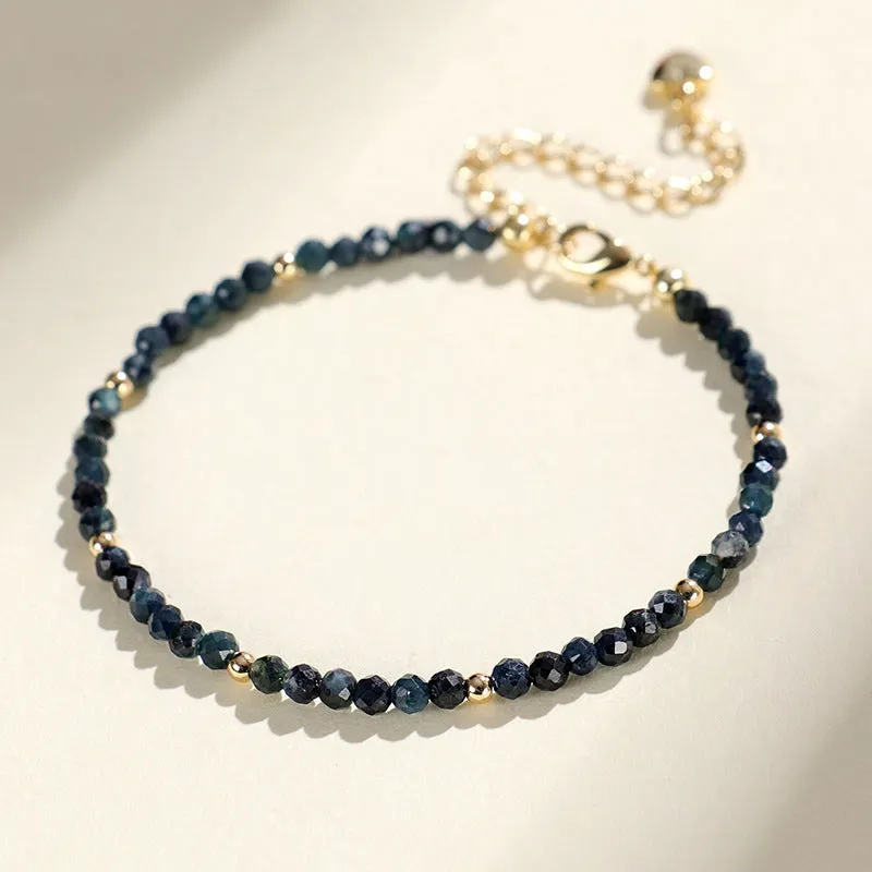 Close-up of a women's bracelet with 3mm blue tourmaline cut beads and silver-toned spacer beads on a wrist.