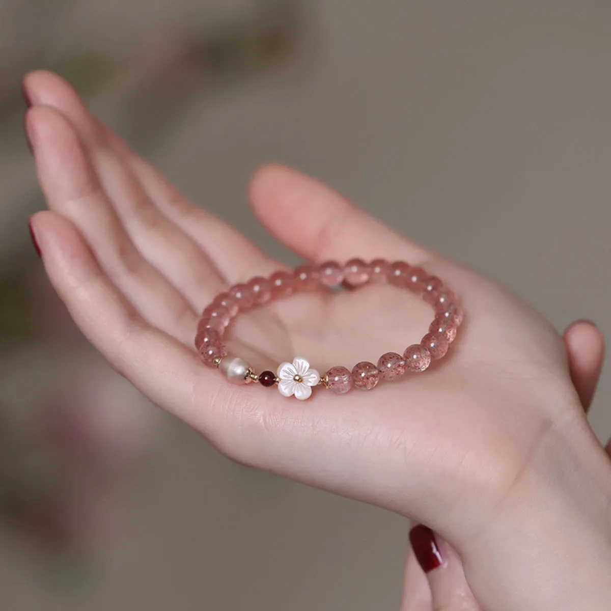 Women's strawberry quartz crystal bracelet with peach blossom flower bead design on wrist