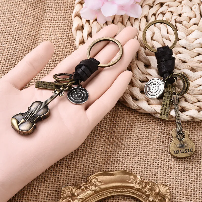 Retro guitar keychain pendant with woven cowhide charm and electroplated alloy finish on white background