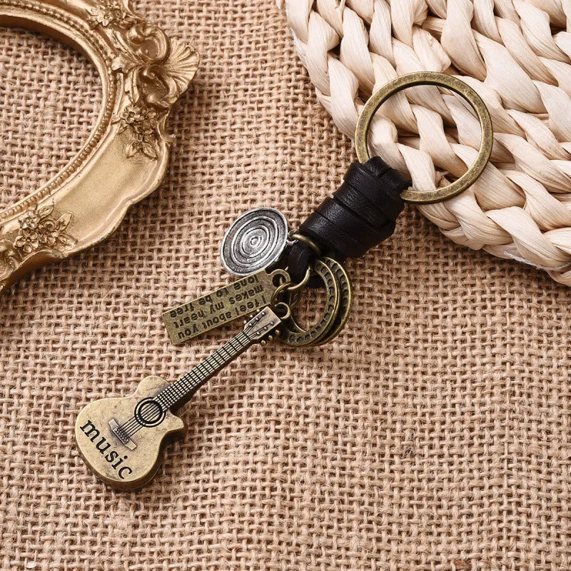 Retro guitar keychain pendant with woven cowhide charm and electroplated alloy finish on white background