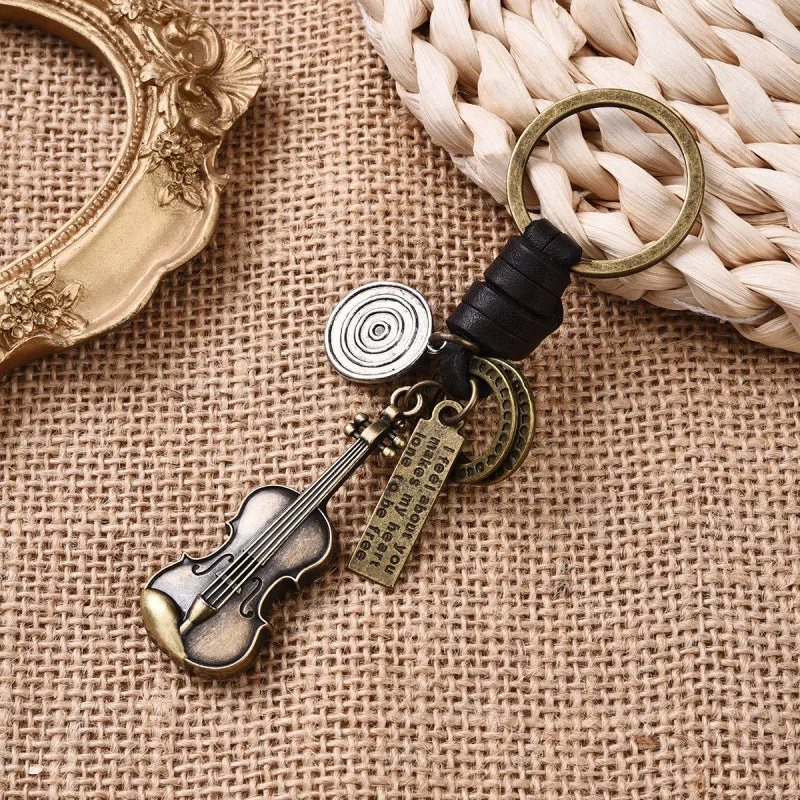 Retro guitar keychain pendant with woven cowhide charm and electroplated alloy finish on white background