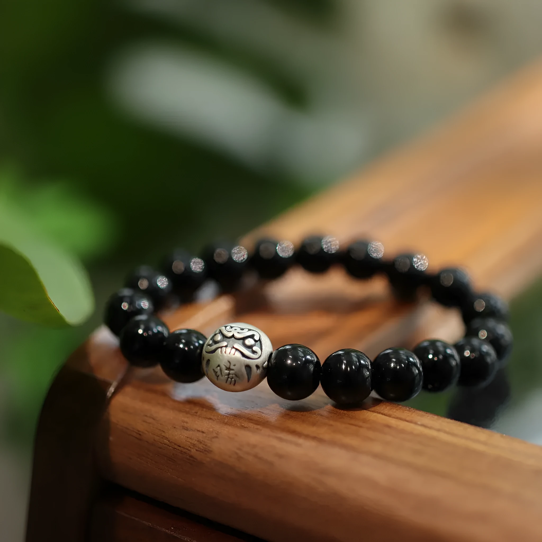 Close-up of a women's black agate bracelet with a sterling silver clasp on an alloy chain.