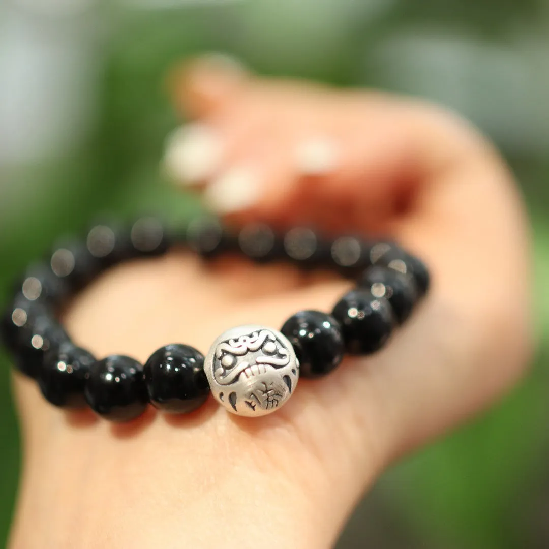 Close-up of a women's black agate bracelet with a sterling silver clasp on an alloy chain.
