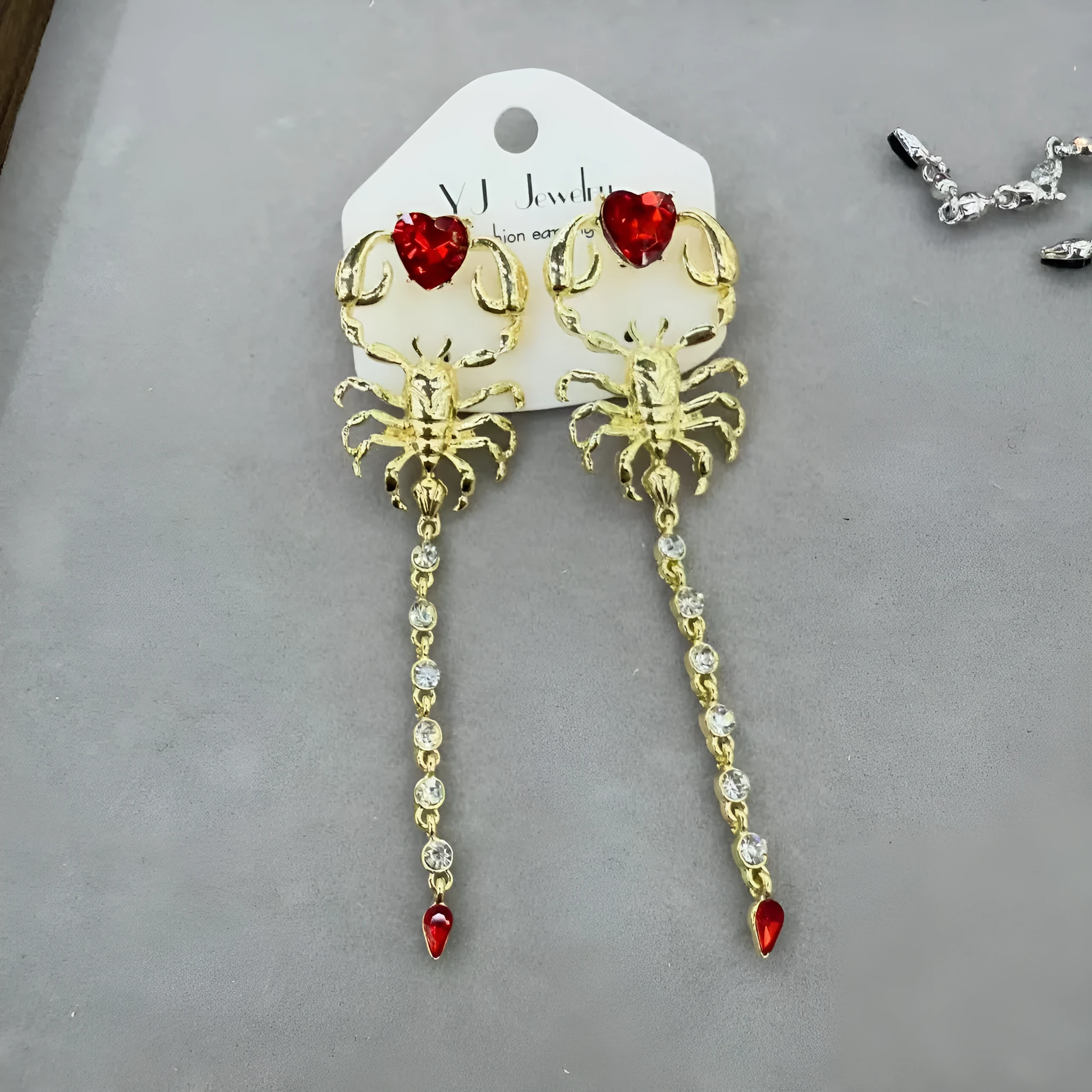 Gold exaggerated insect asymmetric earrings for women on white background with hook fastening