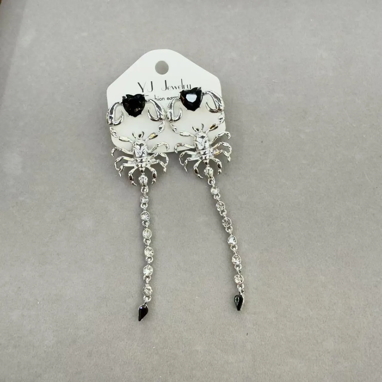 Gold exaggerated insect asymmetric earrings for women on white background with hook fastening