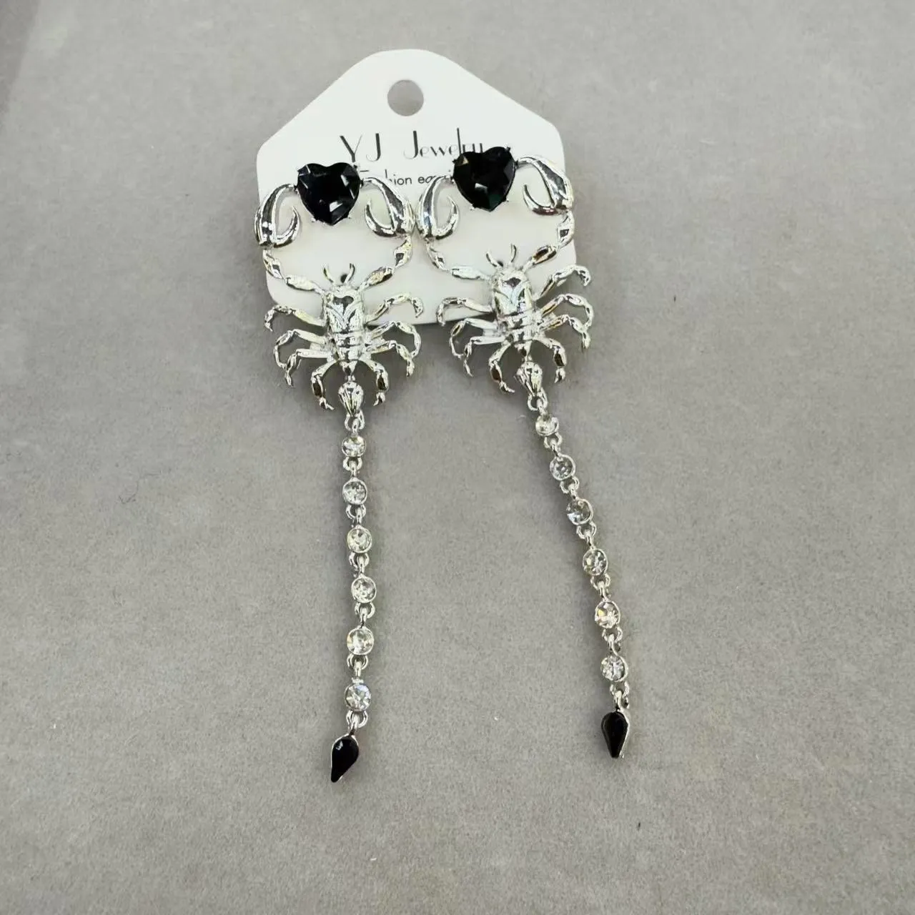 Gold exaggerated insect asymmetric earrings for women on white background with hook fastening