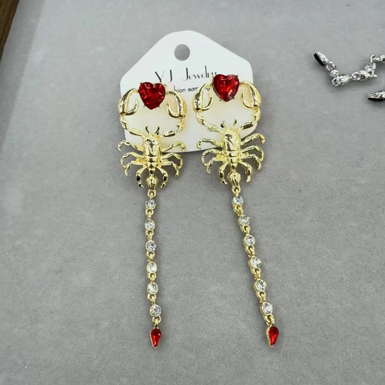 Gold exaggerated insect asymmetric earrings for women on white background with hook fastening