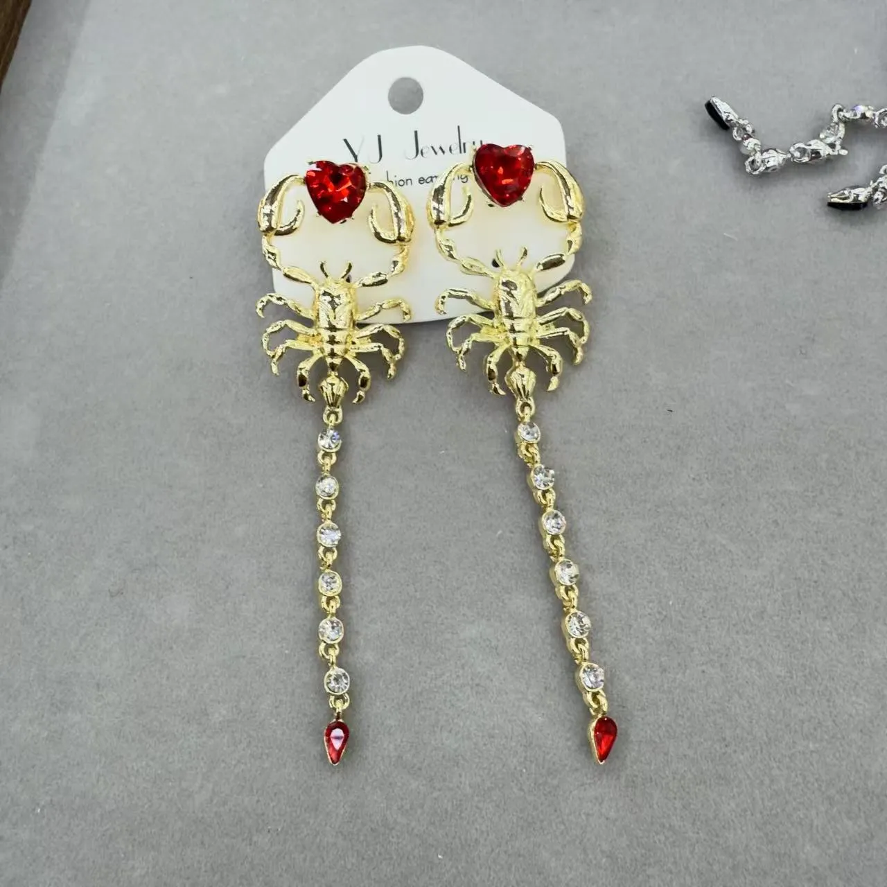 Gold exaggerated insect asymmetric earrings for women on white background with hook fastening