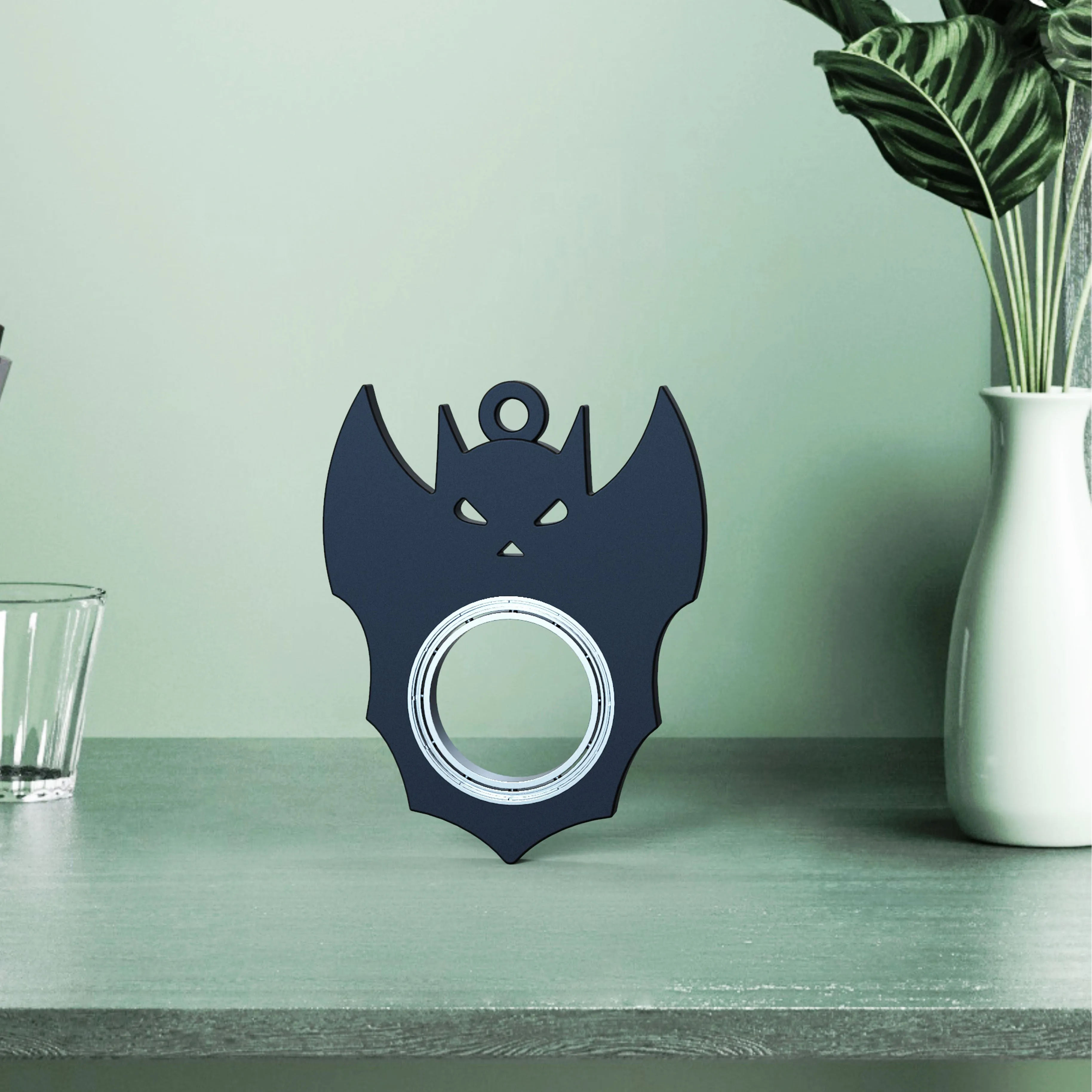 Black plastic Halloween bat demon ghost fidget spinner keychain with bottle opener on a dark background