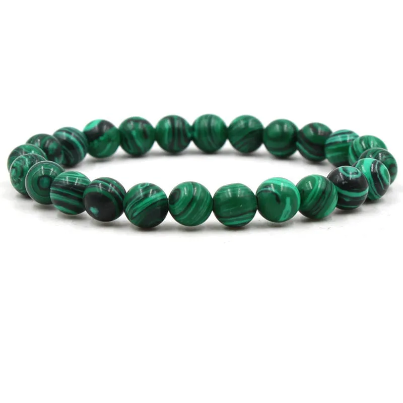 Malachite green and black matte 8mm round bead elastic strand bracelet on a neutral background