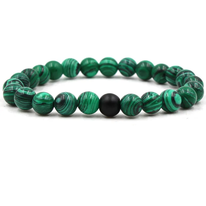 Malachite green and black matte 8mm round bead elastic strand bracelet on a neutral background