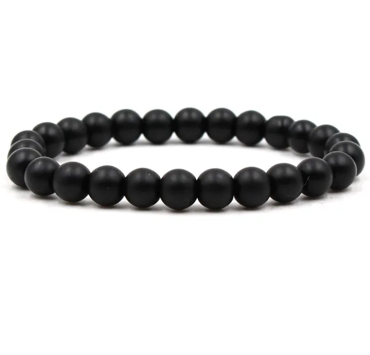 Malachite green and black matte 8mm round bead elastic strand bracelet on a neutral background