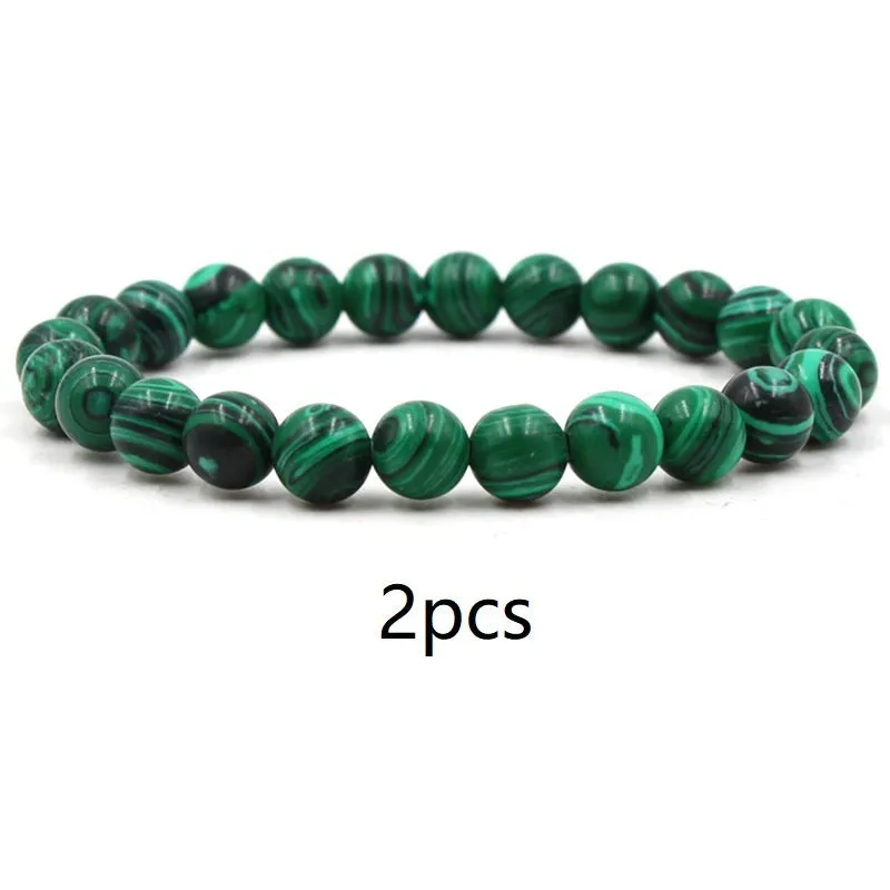 Malachite green and black matte 8mm round bead elastic strand bracelet on a neutral background