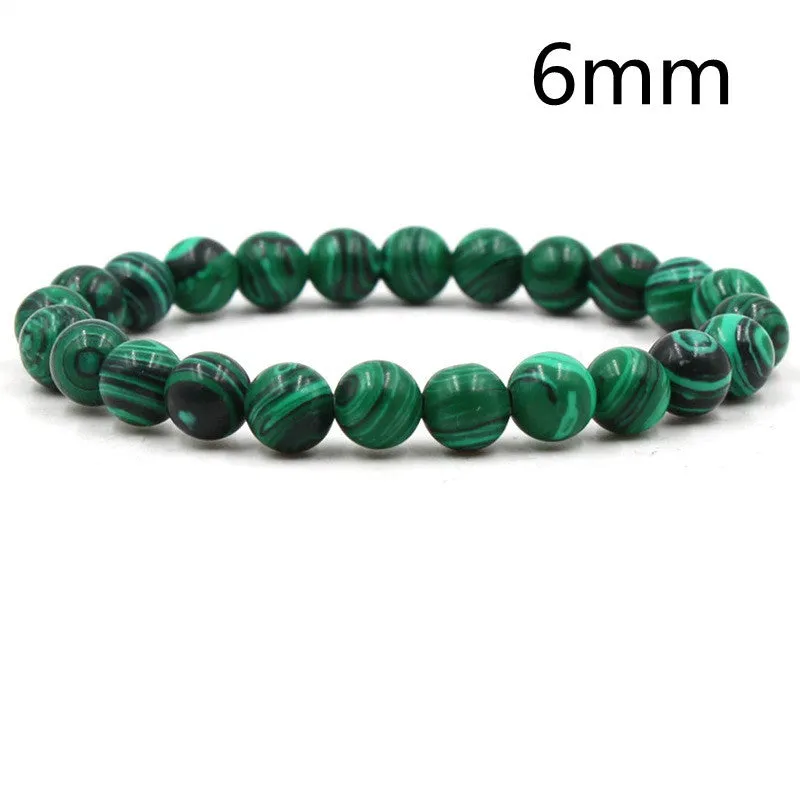 Malachite green and black matte 8mm round bead elastic strand bracelet on a neutral background