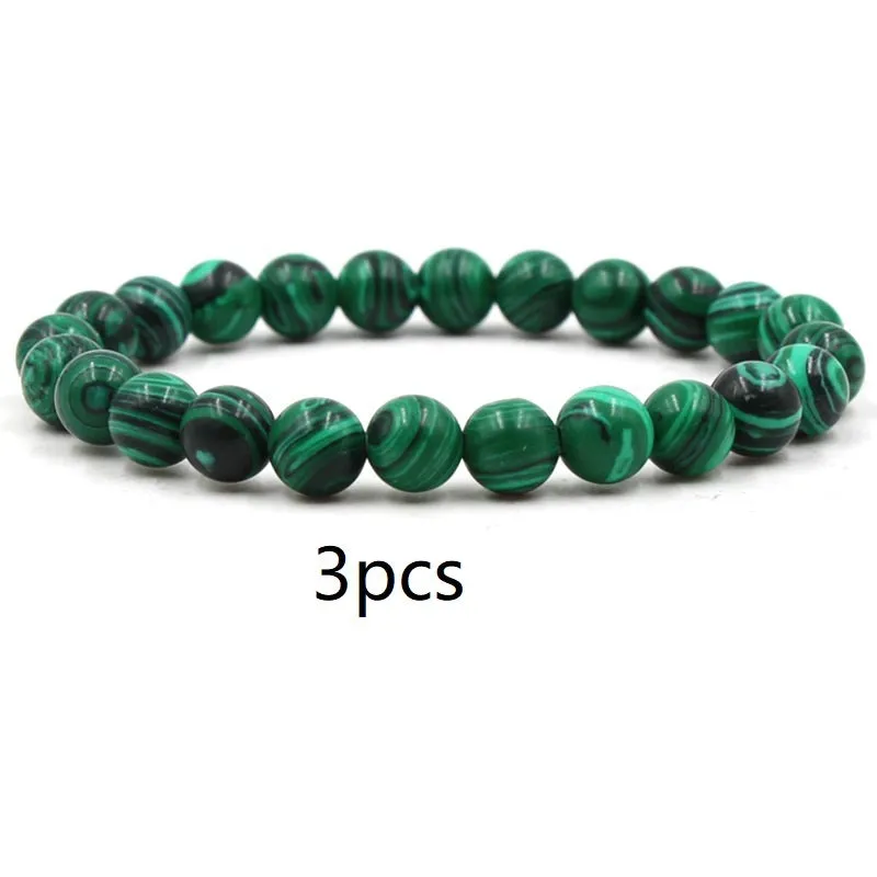 Malachite green and black matte 8mm round bead elastic strand bracelet on a neutral background