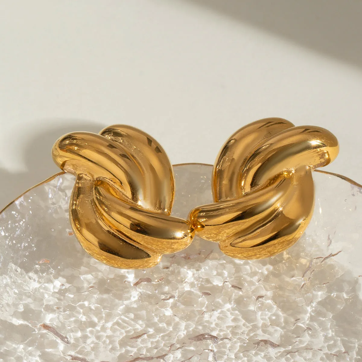 Close-up of women's stainless steel cross-knotted geometric earrings with electroplated finish, 1.5 cm diameter