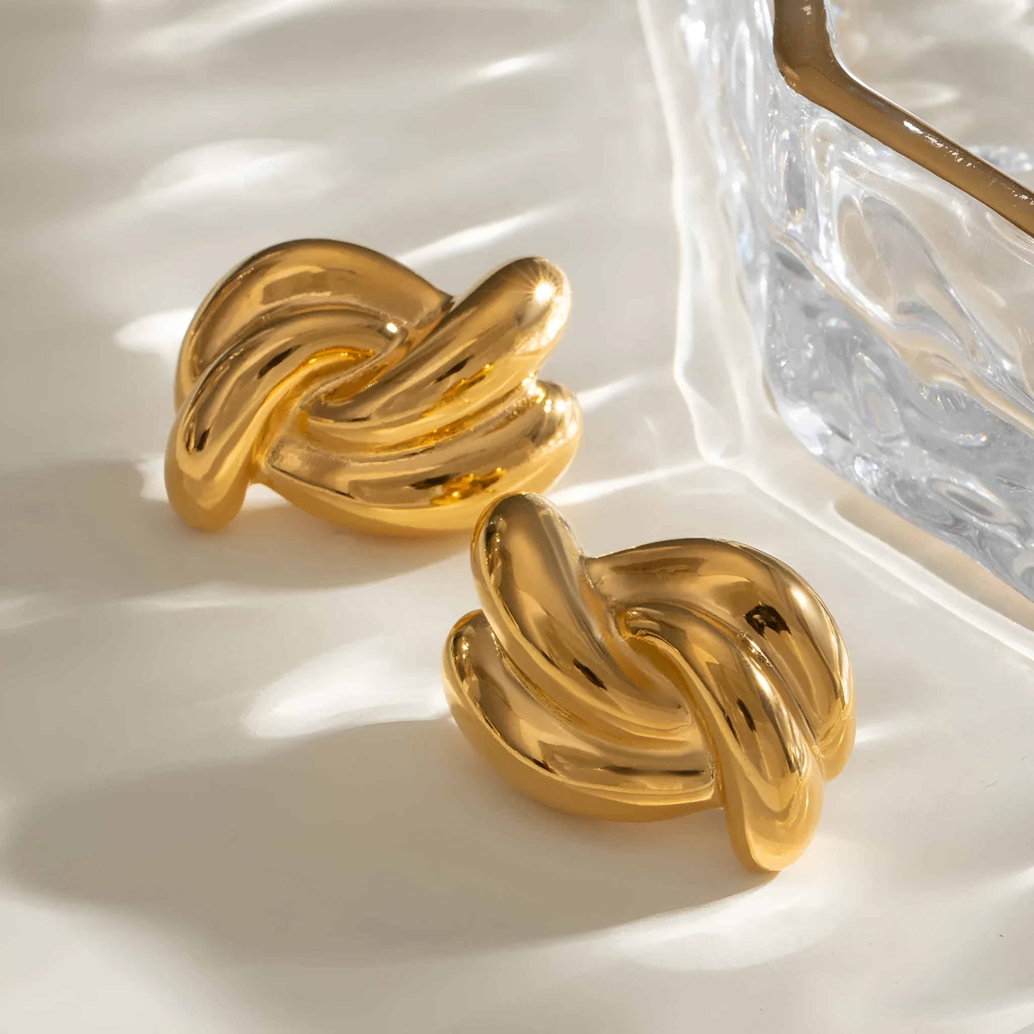Close-up of women's stainless steel cross-knotted geometric earrings with electroplated finish, 1.5 cm diameter