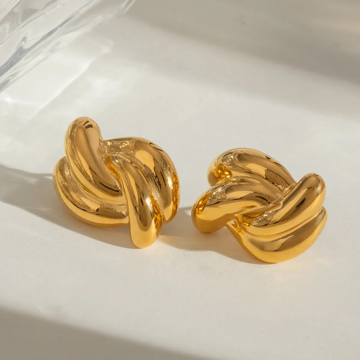 Close-up of women's stainless steel cross-knotted geometric earrings with electroplated finish, 1.5 cm diameter